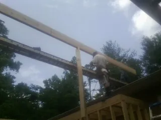Carpenter setting a ridge beam over a new addition frame — Ice Dam Removal by Roofing Brothers in Quitman
