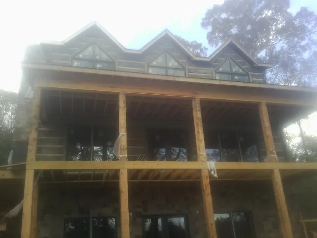 Dormers and porch framing on a large log home under construction — Roof Coating work by our crew in Quitman